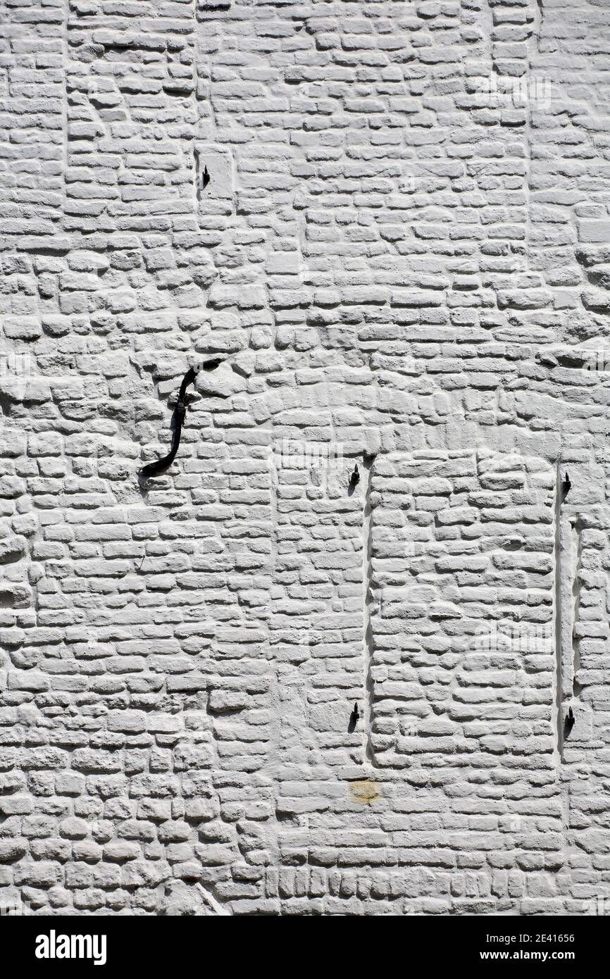 Weiß geschmälerte Ziegelmauer im Streiflicht, Vermauerte Fenster Stockfoto