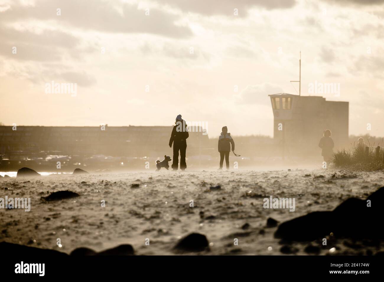 Kiel, Deutschland. Januar 2021, 21. Menschen, die am Strand bei stürmischem Wetter gegen das Licht laufen. Kredit: Frank Molter/Alamy Live Nachrichten Stockfoto
