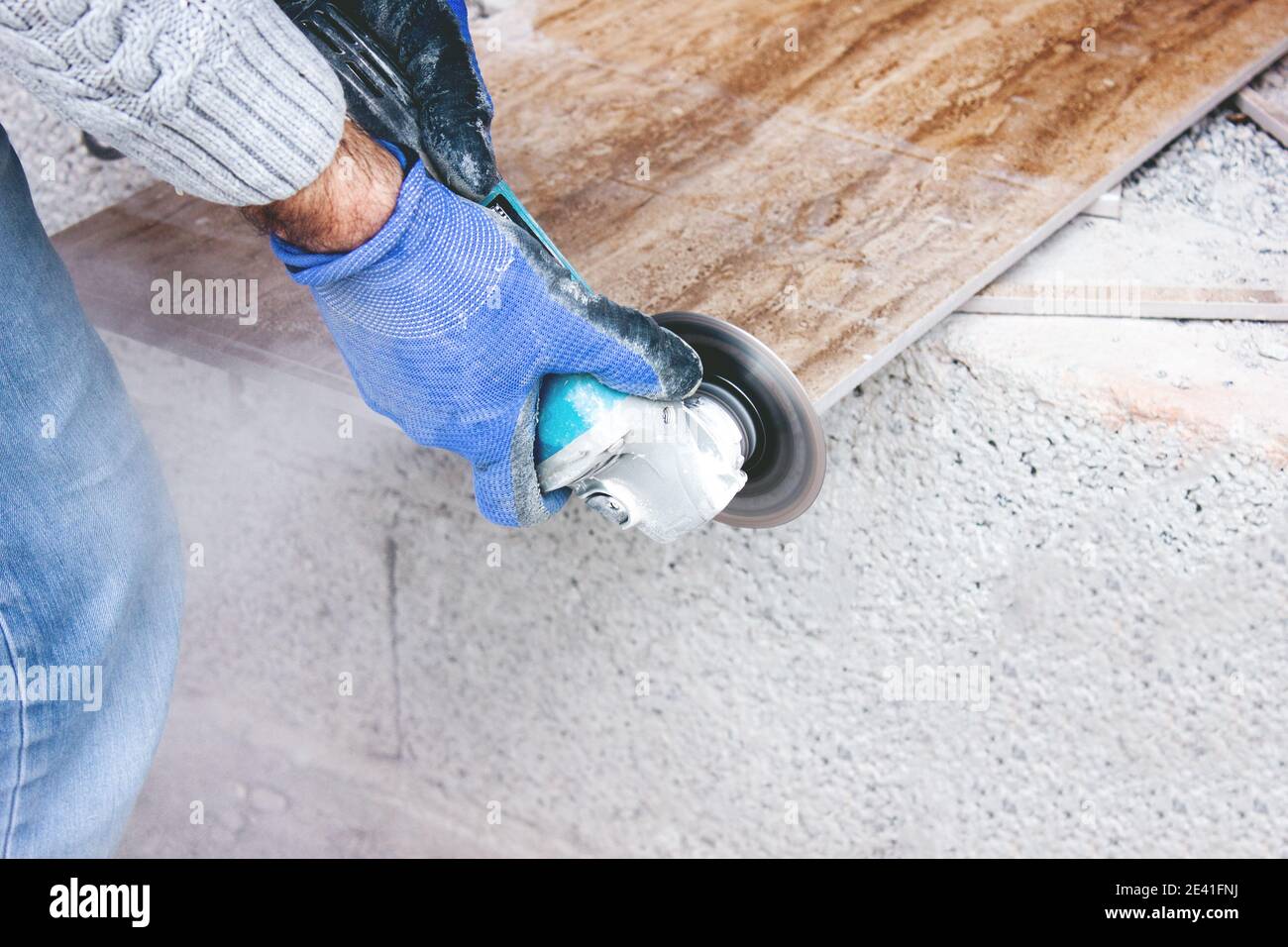 Der Fliesenleger schneidet Fliesen professionell und effizient mit einem Winkel Mahlwerk Stockfoto