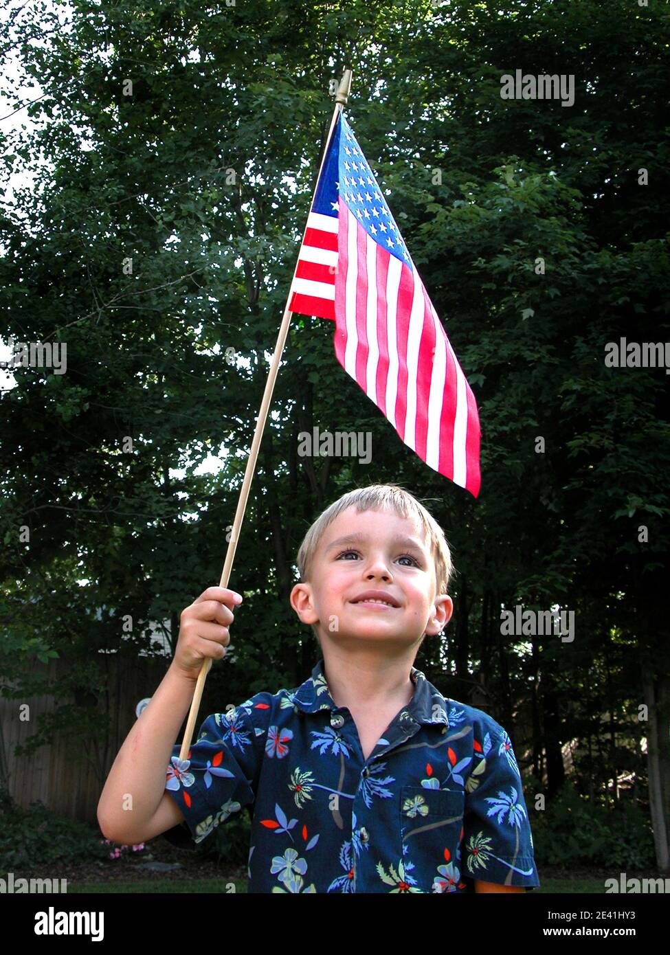 Kleiner Junge hält eine US-Flagge über seinem Kopf hinein Eine patriotische Pose Stockfoto