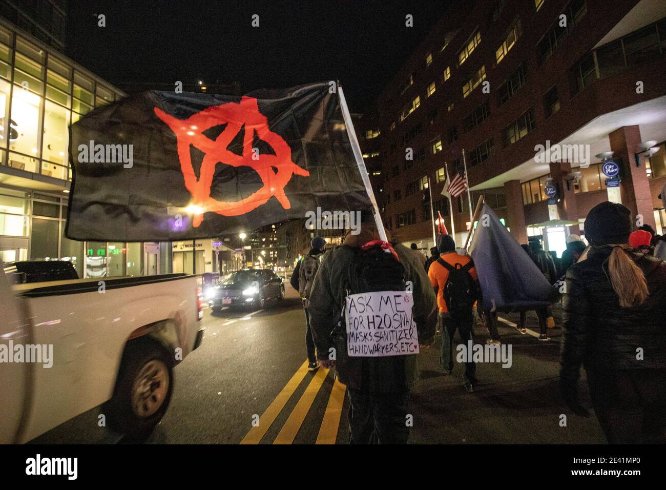 20. Januar 2021, Boston, Massachusetts, USA: Anti-Trump-Protestler mit einer Anarchie-Flagge, die ein Care Pack bei einem marsch durch die Innenstadt von Boston trägt, nach der Kundgebung "Keine Flitterwochen für Biden", die eine progressive Agenda für eine neu gewählte Biden-Harris-Regierung auf Boston Common fordert. Quelle: Keiko Hiromi/AFLO/Alamy Live News Stockfoto