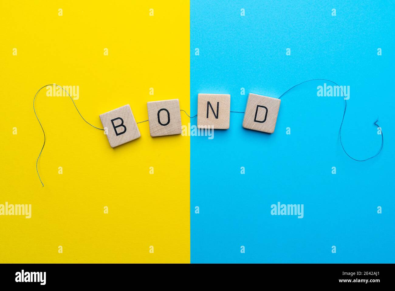Das Wort Bond formte sich mit den Buchstaben, die miteinander verbunden sind Ein Thread Stockfoto