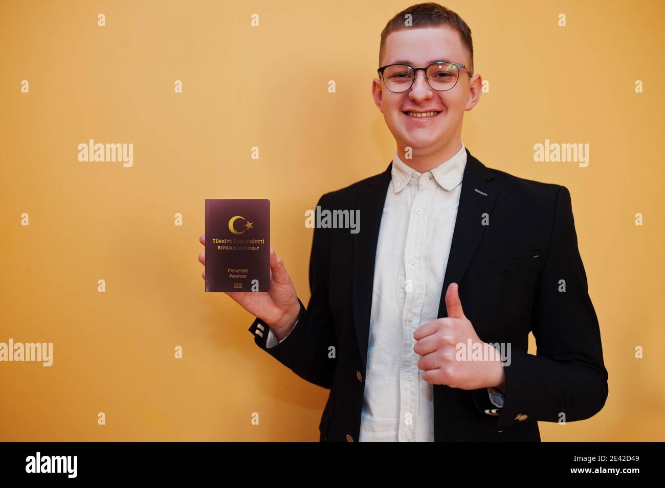 Junger, hübscher Mann, der einen reisepass der Republik Türkei auf gelbem Hintergrund hält, glücklich und zeigt den Daumen nach oben. Reise nach Europa Country Konzept. Stockfoto