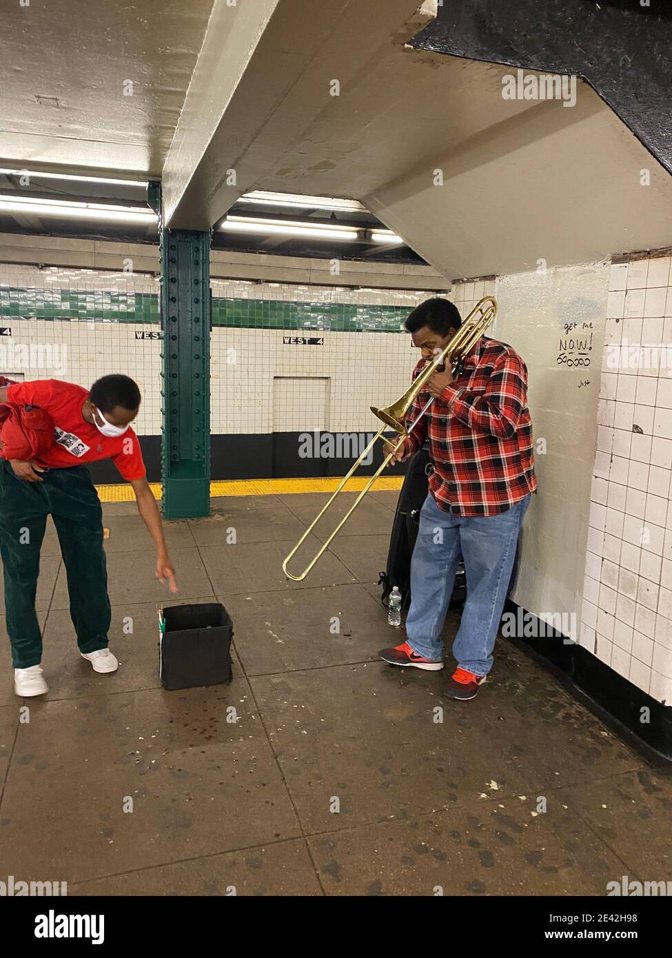 Man zeigt seine Wertschätzung für einen Posaunenspieler in der West 4th Street U-Bahnstation in Greenwich Village, New York City. Stockfoto