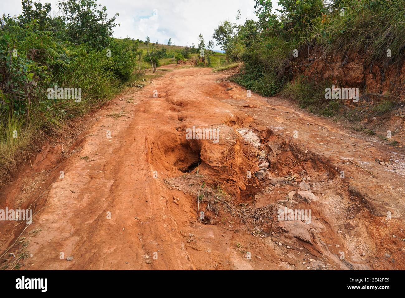 Roter Staub und Schlamm Straße in schlechtem Zustand mit großen Löchern und Beulen nach Regen gebildet. Die Routen zum Nationalpark Andringitra sind bei Nässe extrem schlecht Stockfoto