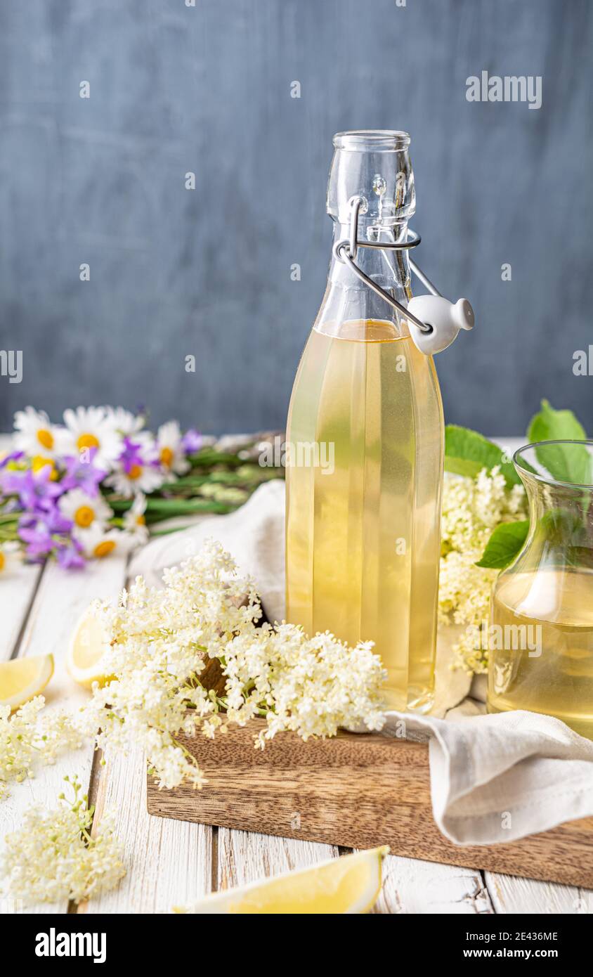 Köstliches gesundes Erfrischungsgetränk, süßer Holunderblütensirup oder Cordial in einer Glasflasche auf rustikalem Holzhintergrund Stockfoto