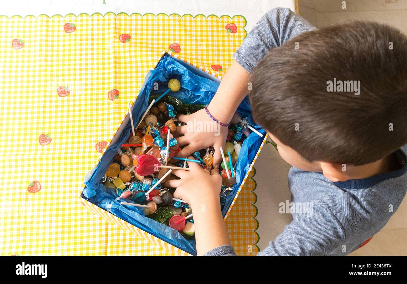 Hände in einer Schachtel mit Süßigkeiten. Kaukasisches Kind, das Süßigkeiten fängt. Stockfoto