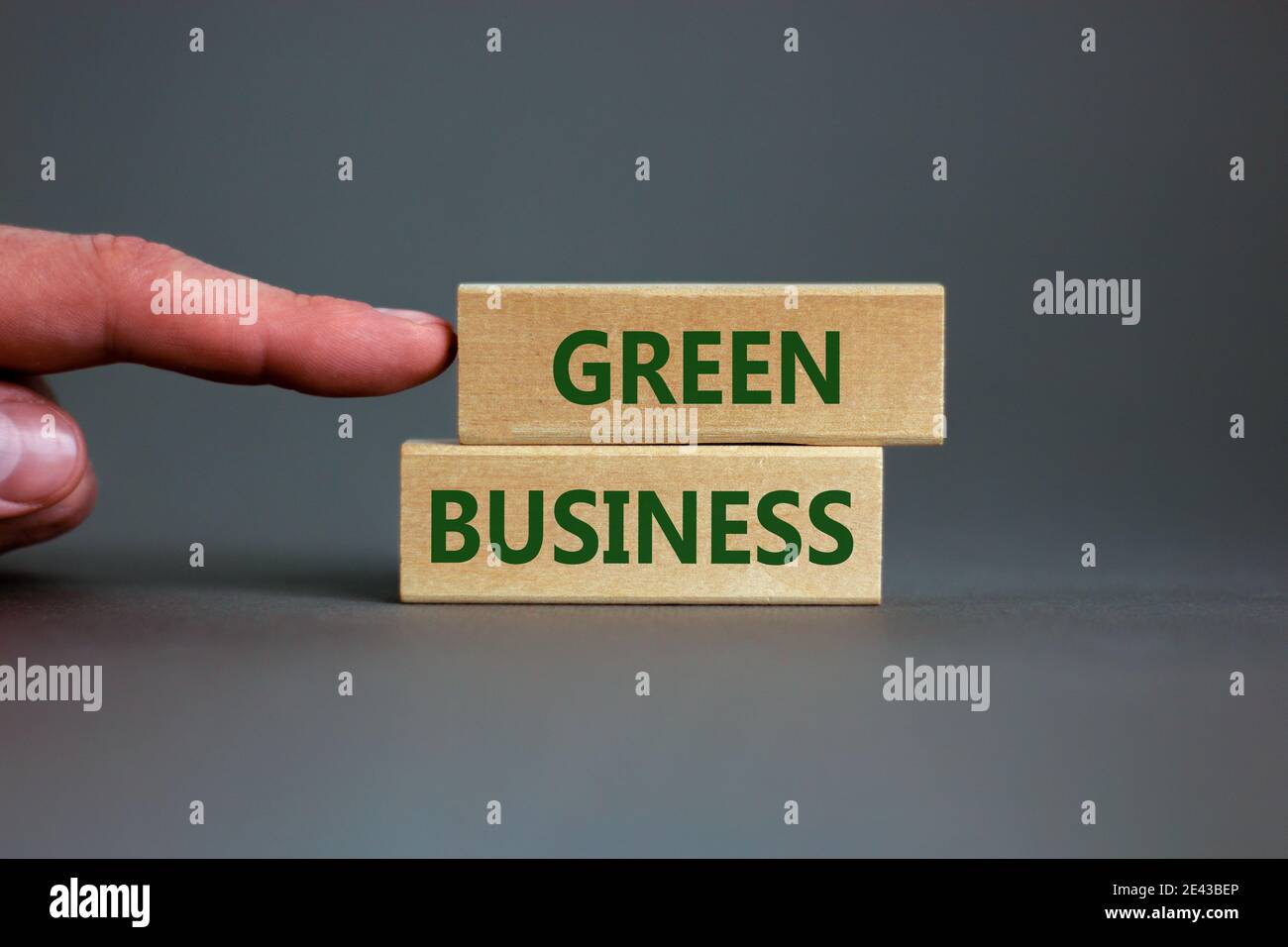 Grünes Geschäftssymbol. Holzblöcke bilden die Worte "Green Business" auf schönem grauen Hintergrund. Geschäftsmann Hand. Business, ökologische und grüne BU Stockfoto