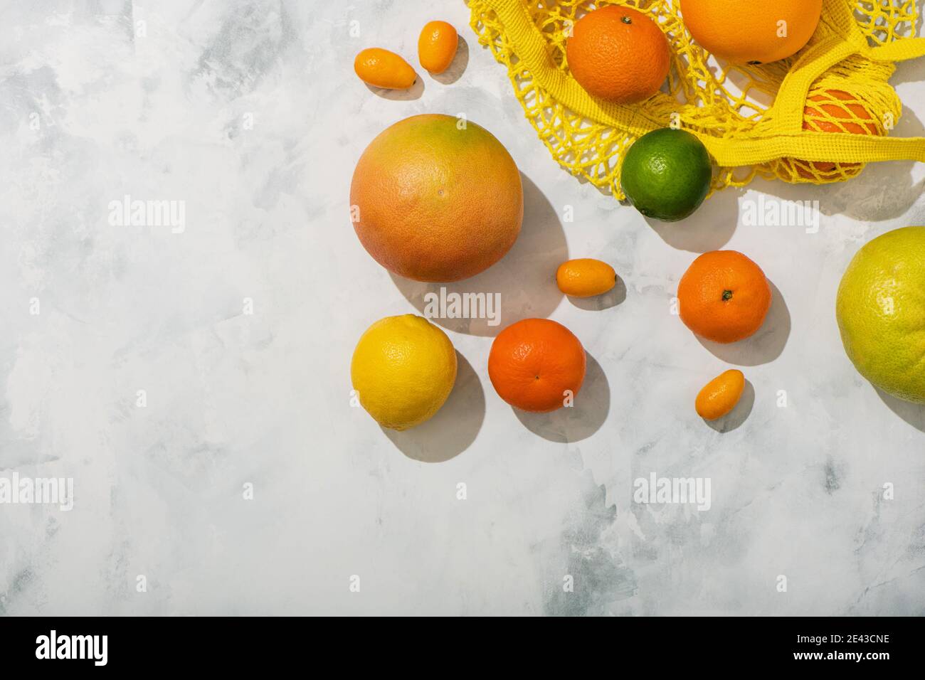 Flatlay mit verschiedenen Zitrusfrüchten in Saitenbeutel auf Marmor Hintergrund. Stockfoto