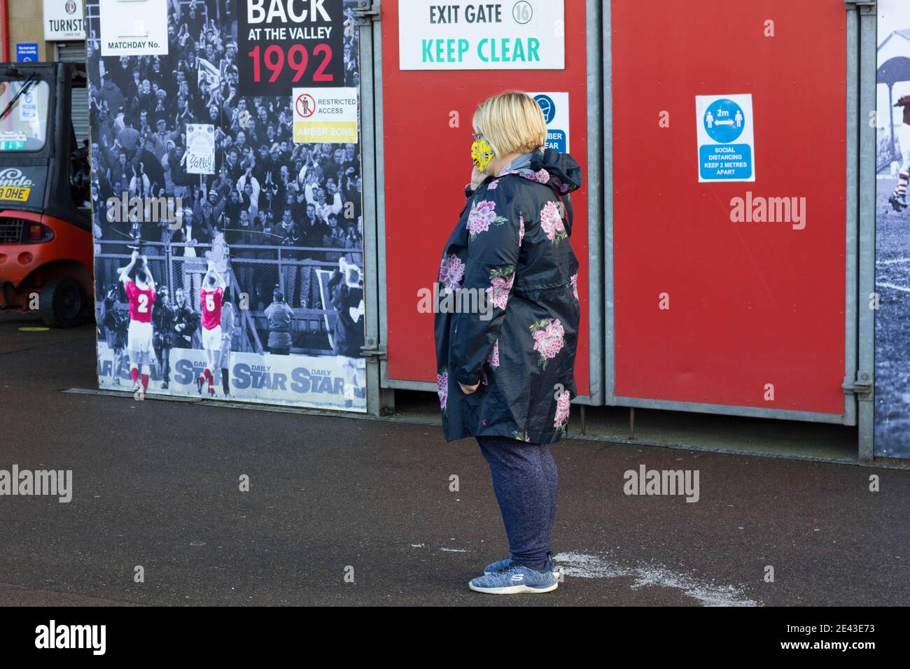 Gesichtsmaske, die Frauen trägt, die in der Warteschlange für den covid-19-Impfstoff im Valley Stadium, Charlton, London, England warten Stockfoto