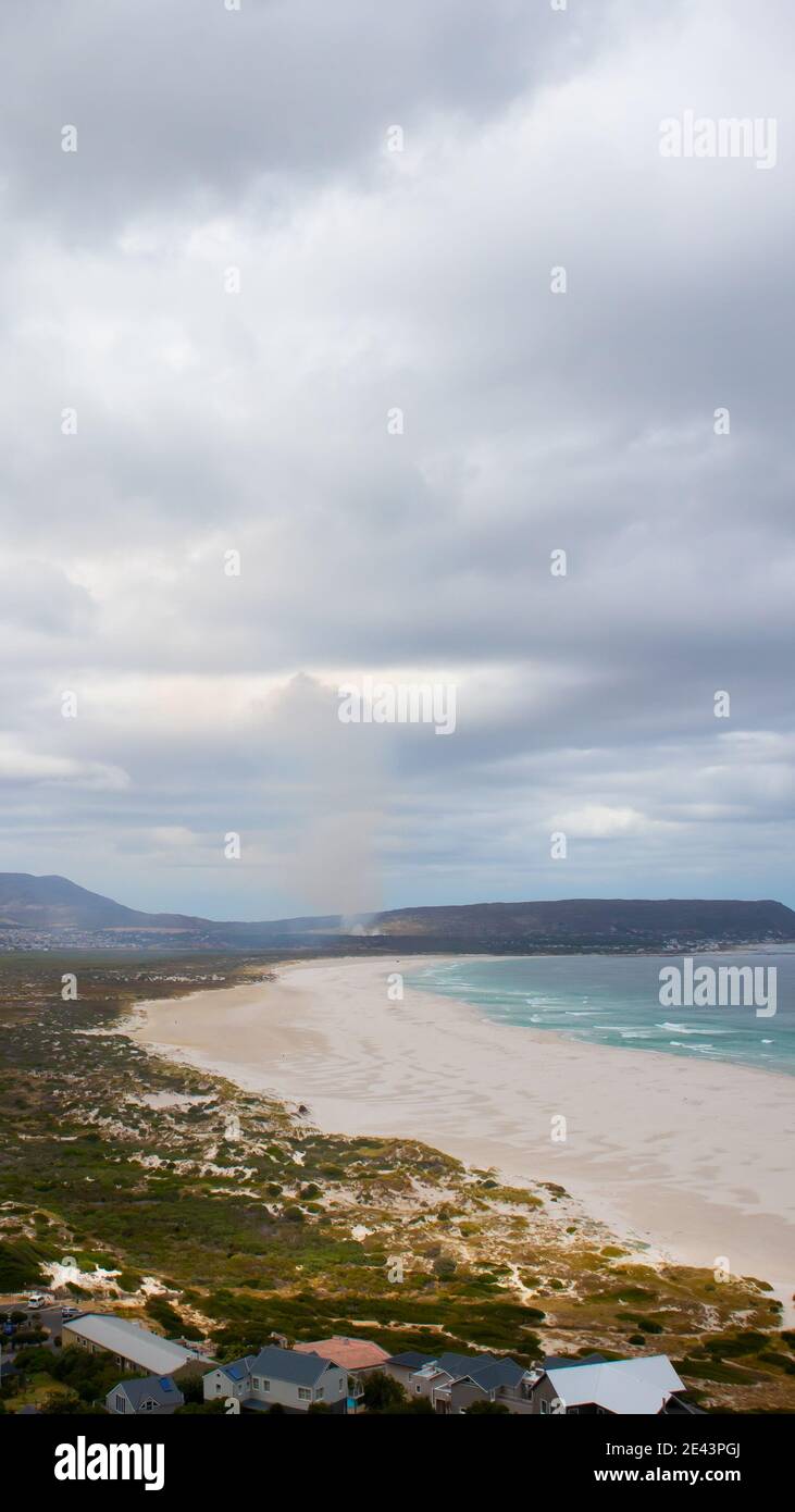 Chapman's Peak - Kapstadt, Südafrika - 19-01-2021 Feuer auf einem Berg, Rauch hebt sich in den Himmel im Hintergrund. Wolkiger Himmel oben. Stockfoto