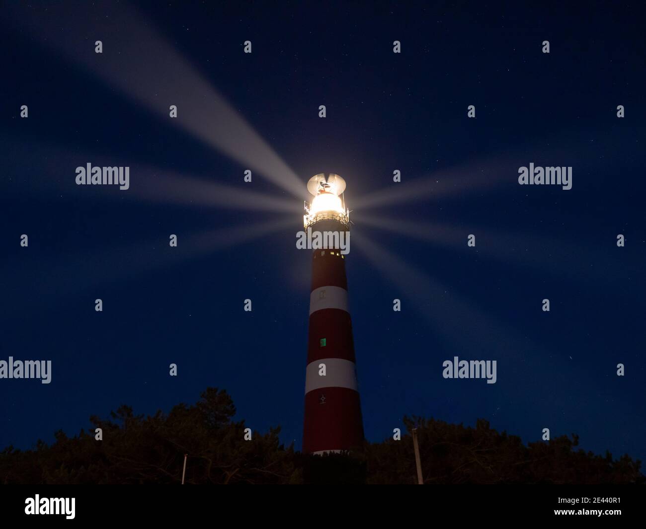 Leuchtturm mit Lichtstrahlen in der Nacht, ein Sternenhimmel auf der Insel Ameland, Hollum, Niederlande. Stockfoto