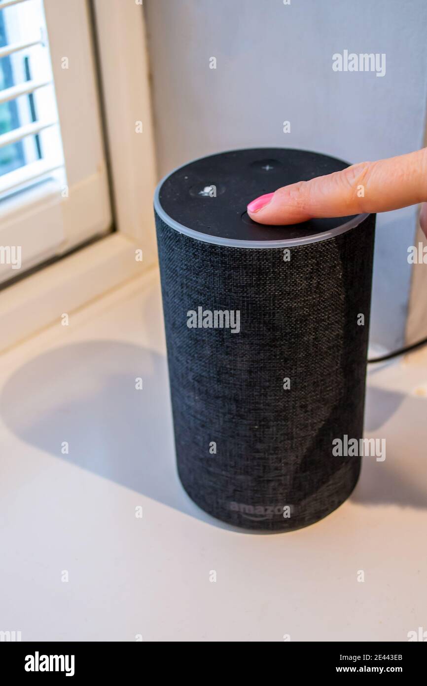 LONDON/ENGLAND- 19. Januar 2020: Frau drückt einen Knopf auf einem Amazon Echo Dot Smart Speaker Stockfoto