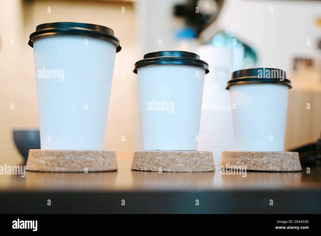 Reihe von verschiedenen Einweg-Pappbecher für Kaffee zum Mitnehmen platziert An der Theke im Coffee Shop Stockfoto