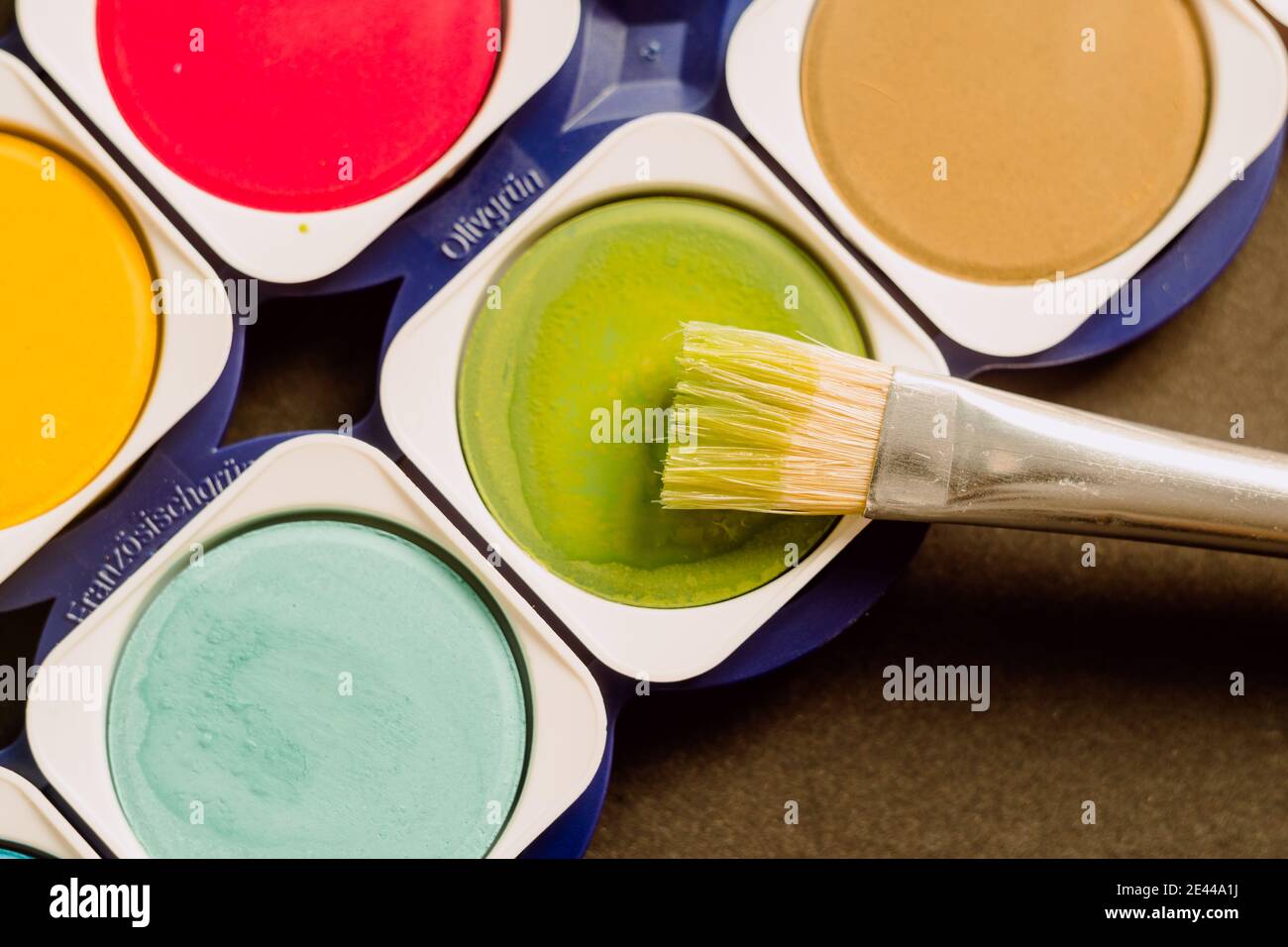 Oben Nahaufnahme der hellen bunten Aquarellfarben mit Pinsel Und Spuren der Bürste in der Schachtel angeordnet Stockfoto