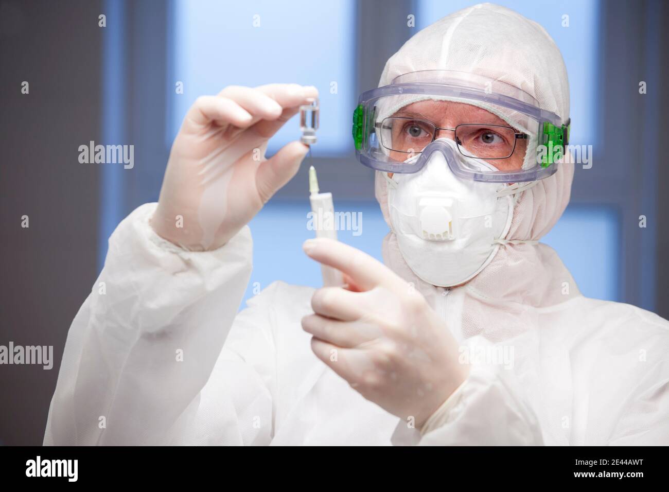 Arzt in weißer Schutzkleidung Vorbereitung einer Spritze für die Impfung - Fokus auf das Gesicht Stockfoto