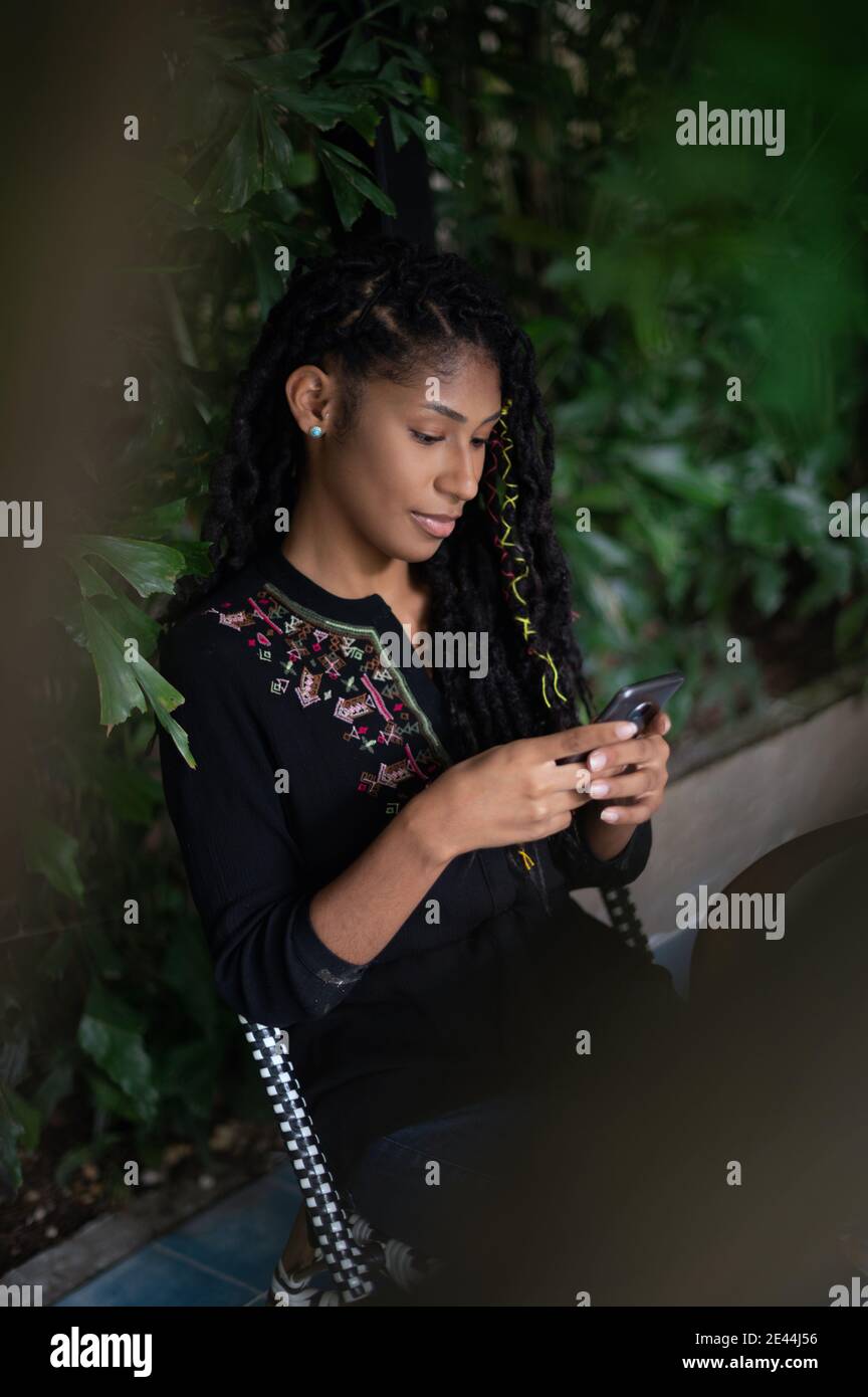 Junge attraktive afro latina Frau mit einem Smartphone, Profilansicht Stockfoto