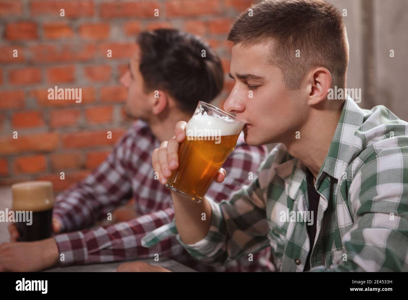 Junger Mann schlürft leckeres Bier im Pub Stockfoto