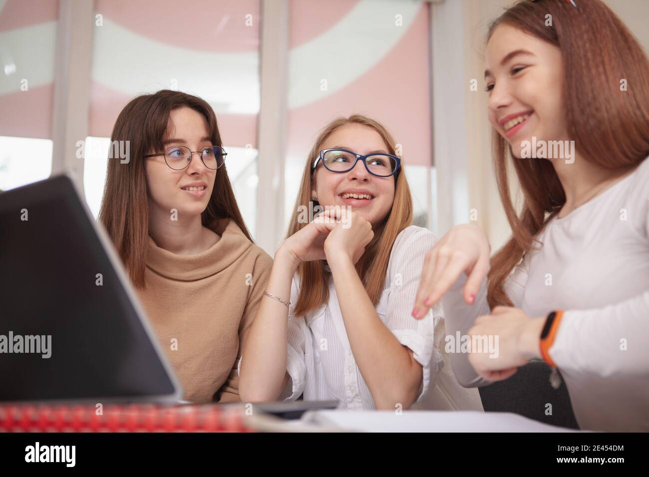 Gruppe von Jugendlichen weiblichen Studenten sprechen während der Lektion. Schöne Teenager-Mädchen diskutieren ihr Projekt, mit Laptop in der Klasse. Bildung, Freundschaft, Technik Stockfoto