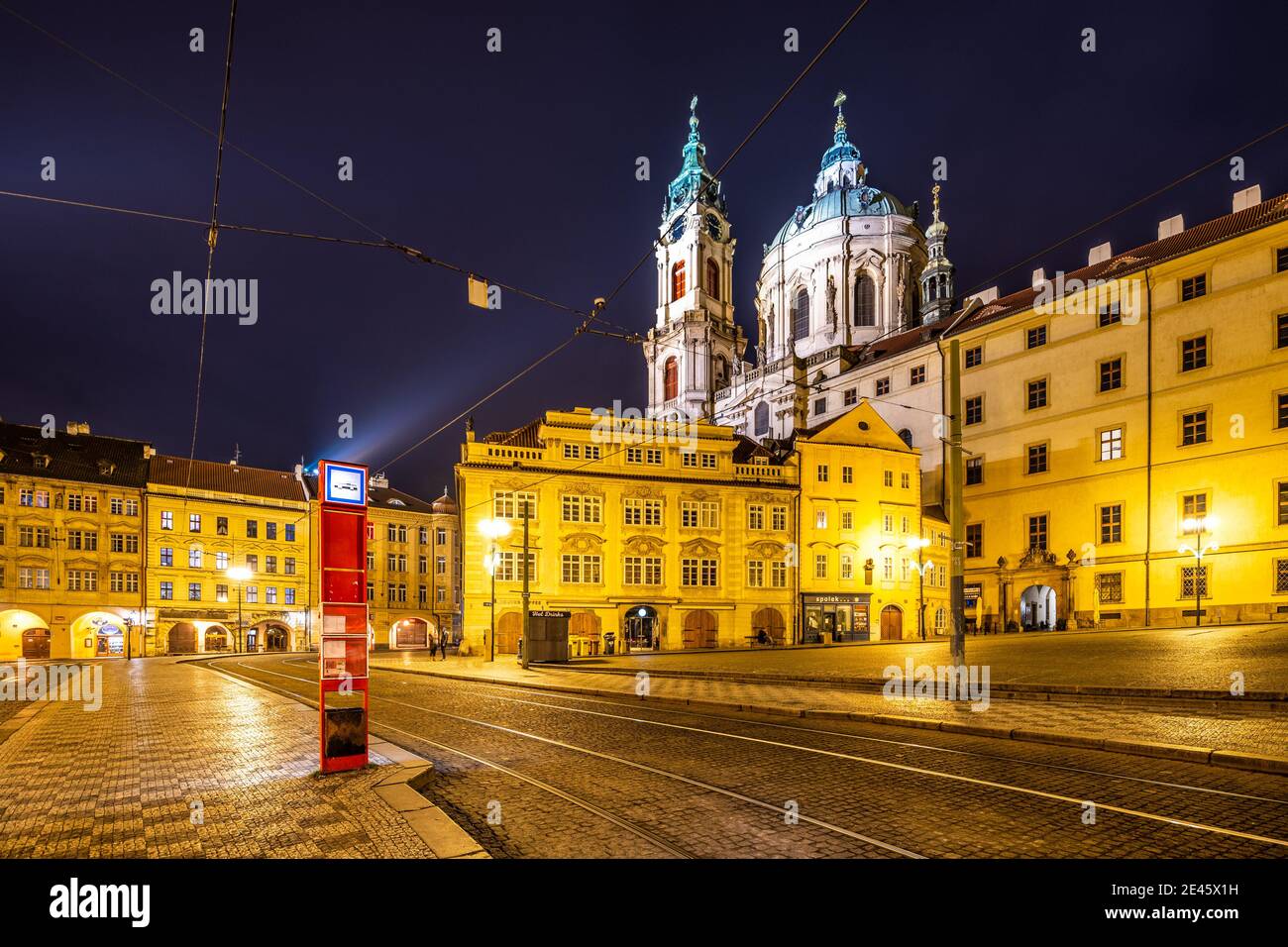 Kleinstadt in Prag bei Nacht. Gepflasterte Straße und beleuchtete Gebäude mit barocker Kuppel der St. Nikolaus-Kirche. Prag, Tschechische Republik Stockfoto