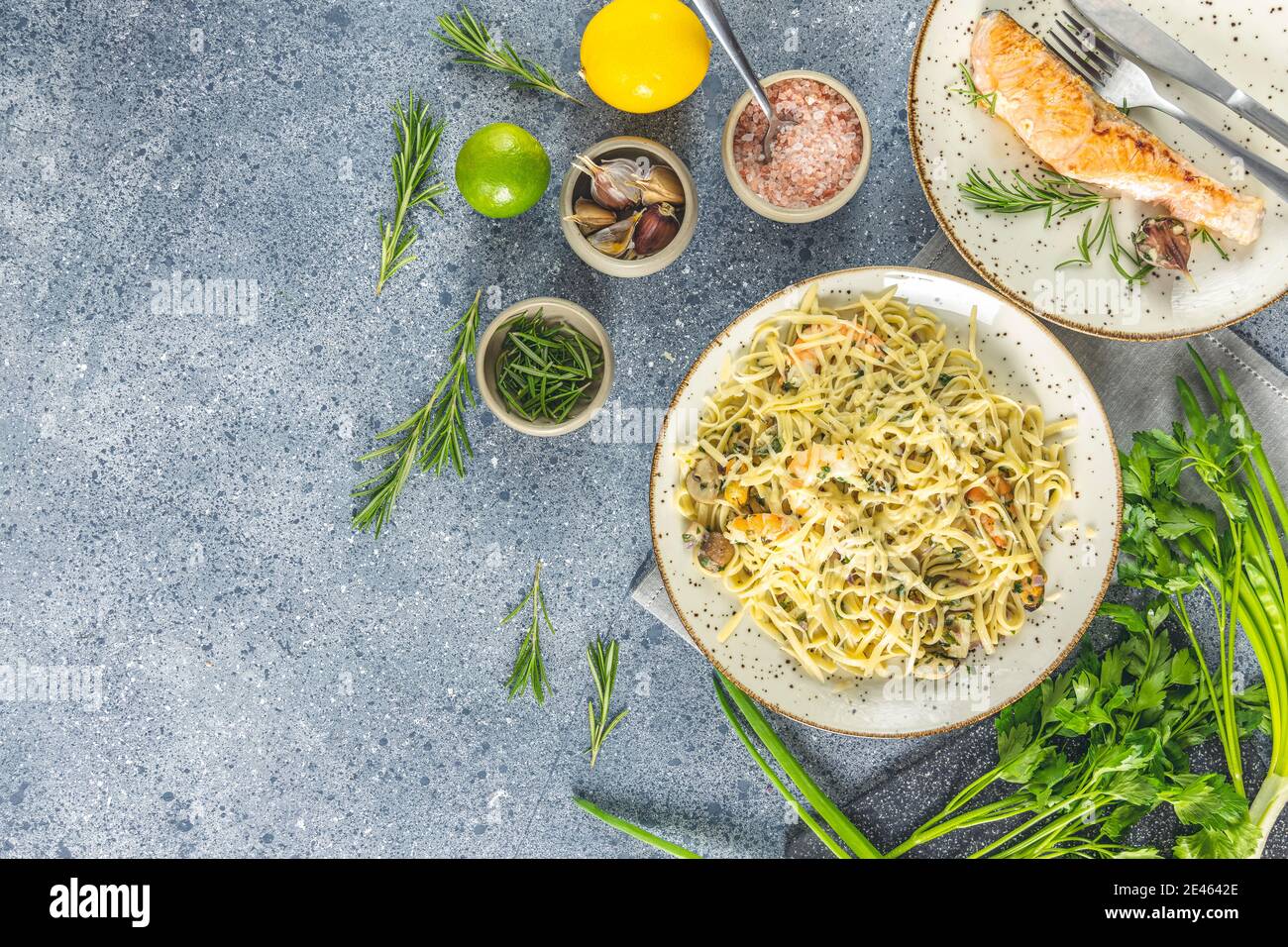 Pasta Linguine mit Pilzen, Garnelen und Meeresfrüchten Muscheln, Käse und Kräutern, in Keramikplatte auf einer hellgrauen Oberfläche. Stockfoto