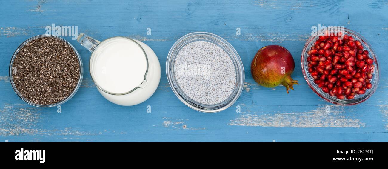 Chia-Samenpudding mit Granatapfelkernen Rezept. Zutaten schließen in einer Linie auf blauem Holzhintergrund, flach legen Stockfoto