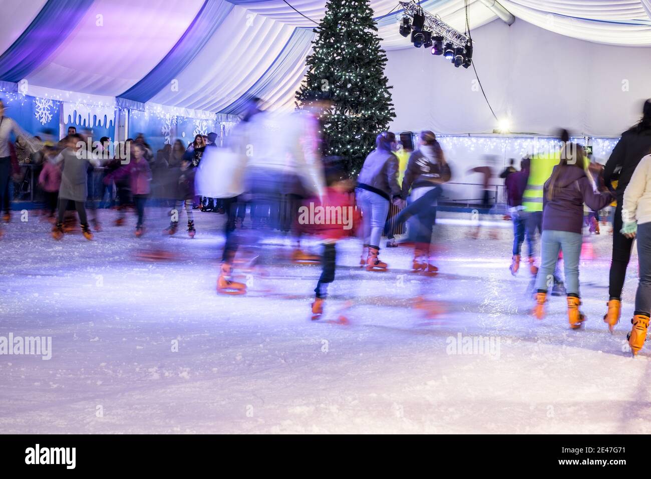 Malaga, Spanien - 08. Dezember 2017. Viele Menschen Schlittschuh auf große Eisbahn in der Winternacht, Bewegungsunschärfe Stockfoto