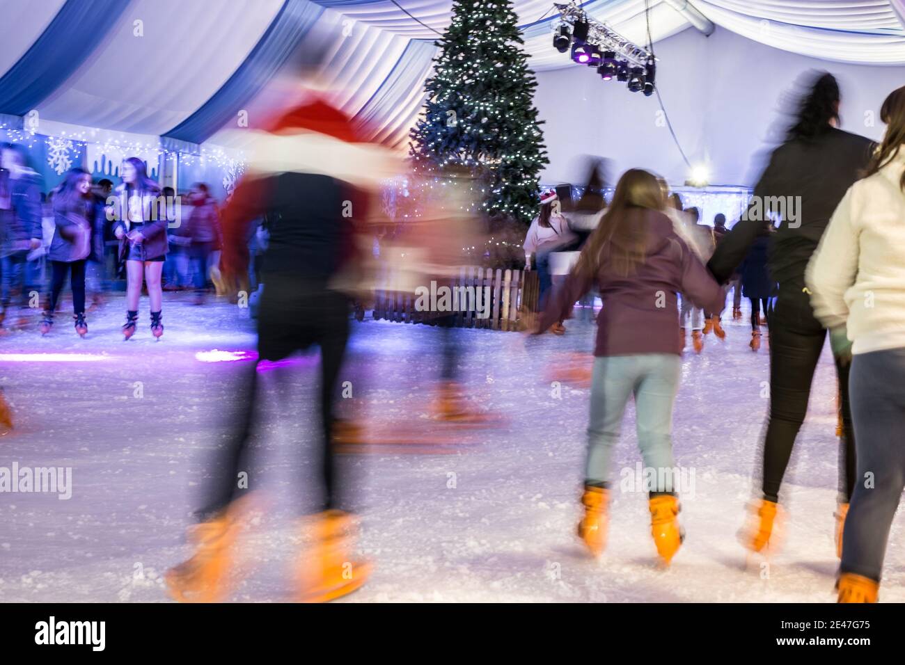 Malaga, Spanien - 08. Dezember 2017. Viele Menschen Schlittschuh auf große Eisbahn in der Winternacht, Bewegungsunschärfe Stockfoto