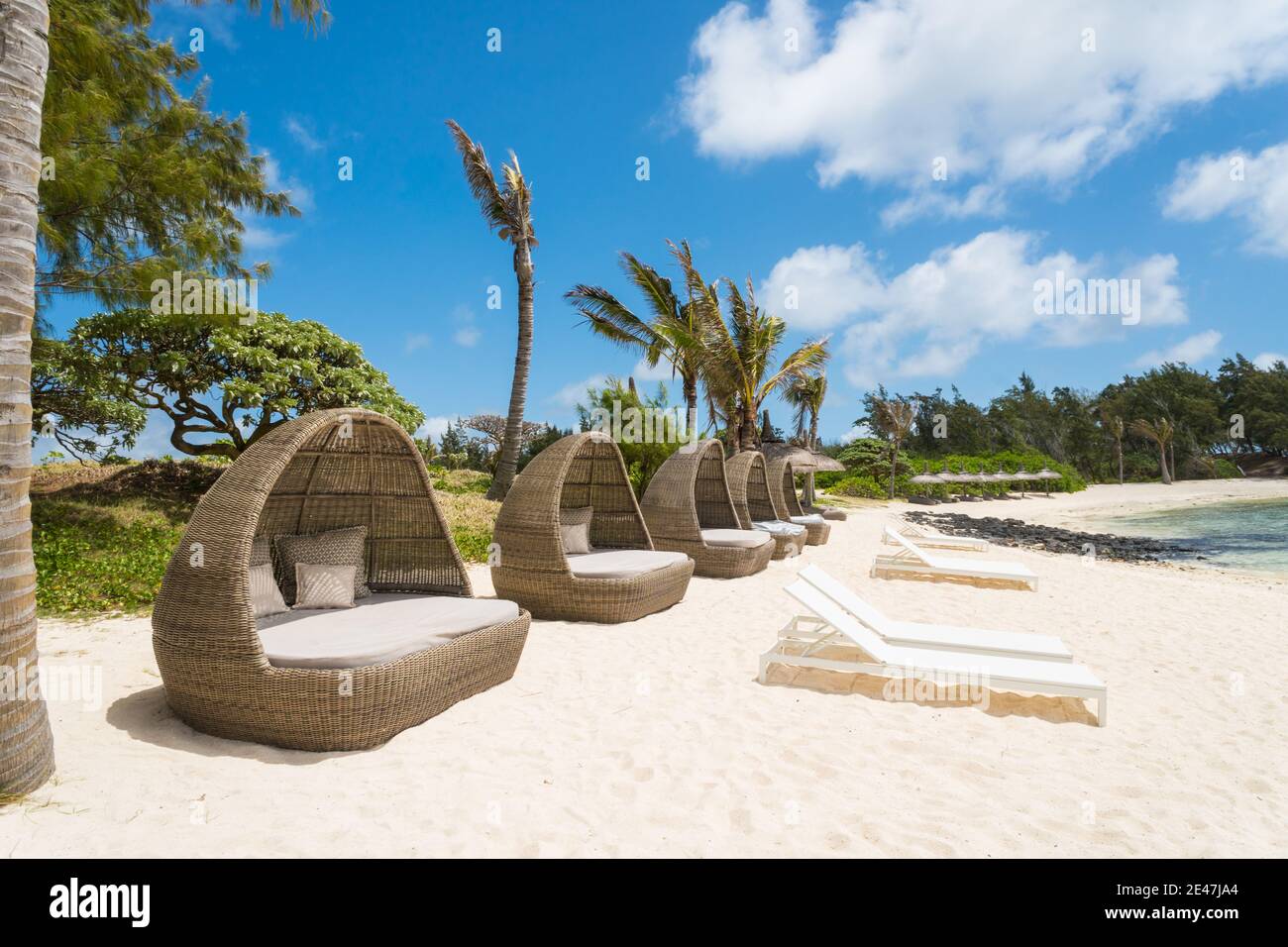 Sonnenliegen, Schoten, Stühle, aus gewebtem Rohr oder Material in einer Reihe an einem weißen Sandstrand auf der tropischen Insel Mauritius ohne Menschen Stockfoto