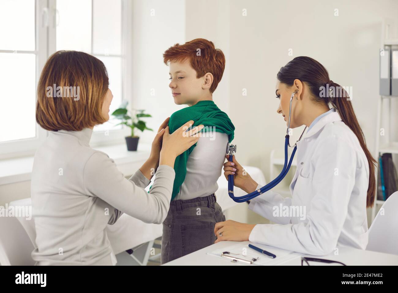 Frau Arzt Kinderarzt Untersuchung kleinen lächelnden Jungen mit Stethoskop Stockfoto