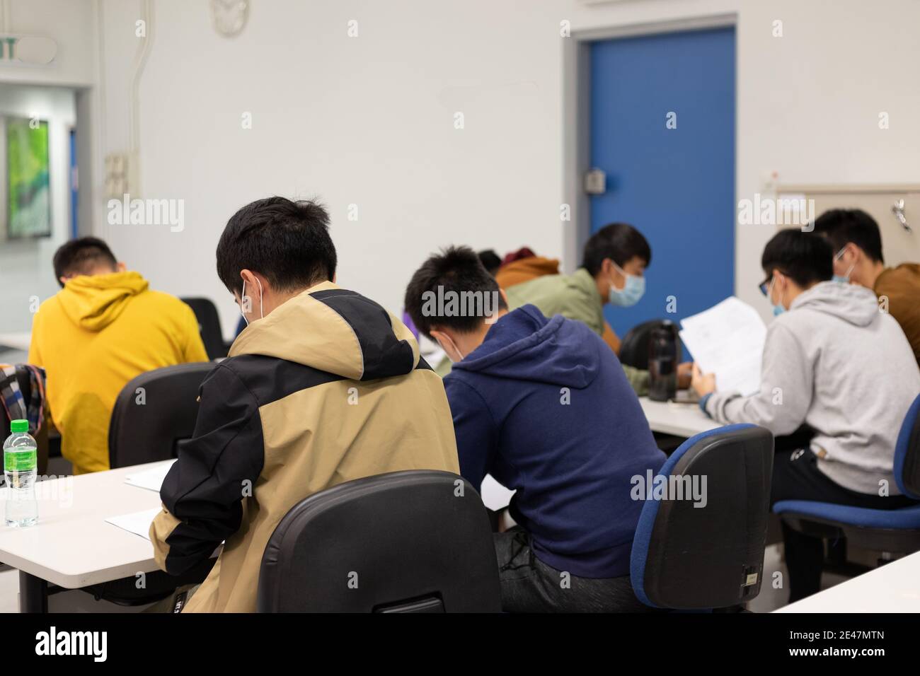 Schüler mit Gesichtsmaske lesen und machen Kursarbeit im Klassenzimmer In der Universität in Hong Kong während Covid-19 Stockfoto