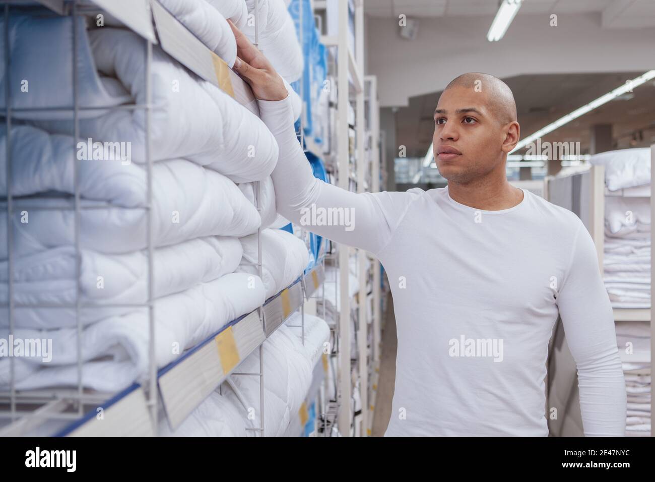 Hübscher junger afrikanischer Mann, der eine neue Decke bei Local auswählt Kaufhaus Stockfoto