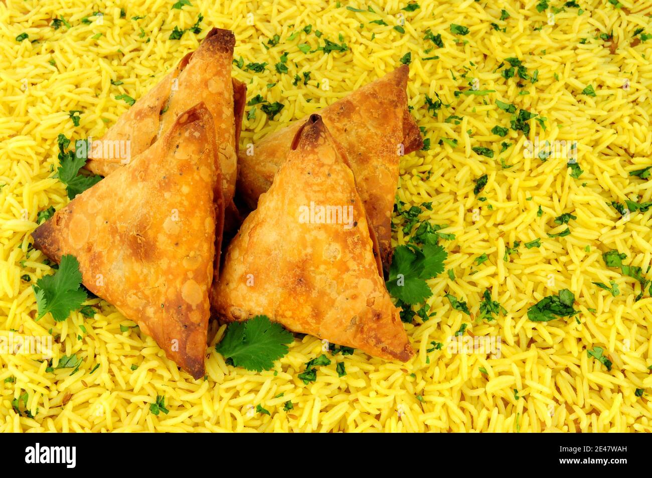Indische würzige Gemüse knusprige Gebäck gefüllt Samosas mit einem Pilau Reishintergrund Stockfoto