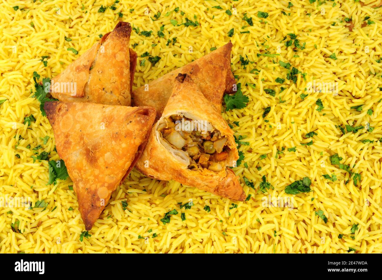 Indische würzige Gemüse knusprige Gebäck gefüllt Samosas mit einem Pilau Reishintergrund Stockfoto