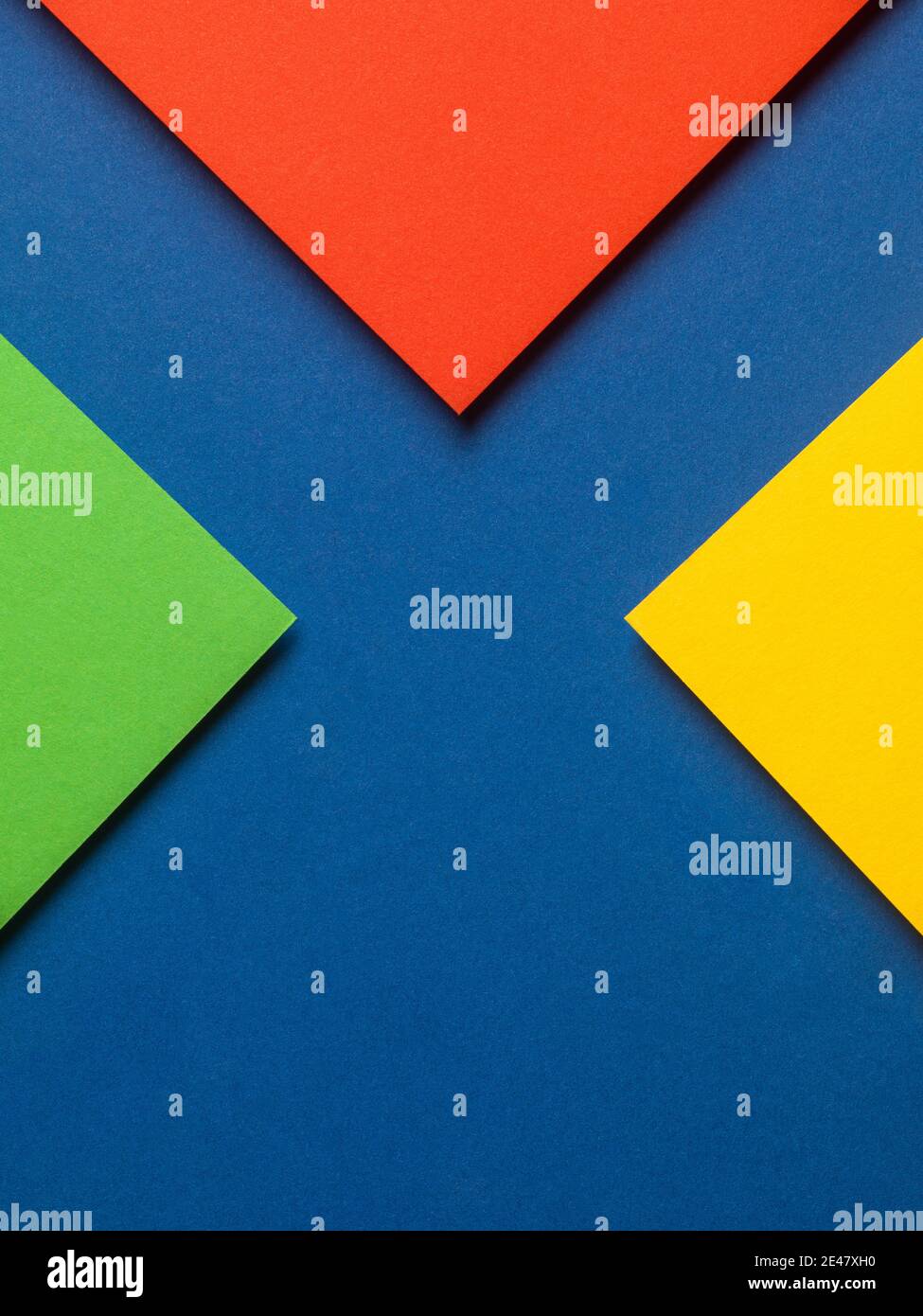 Buntes Papierdesign mit roten, gelben und grünen Dreiecken auf blauem Hintergrund, Web-Design-Ressourcen. Stockfoto