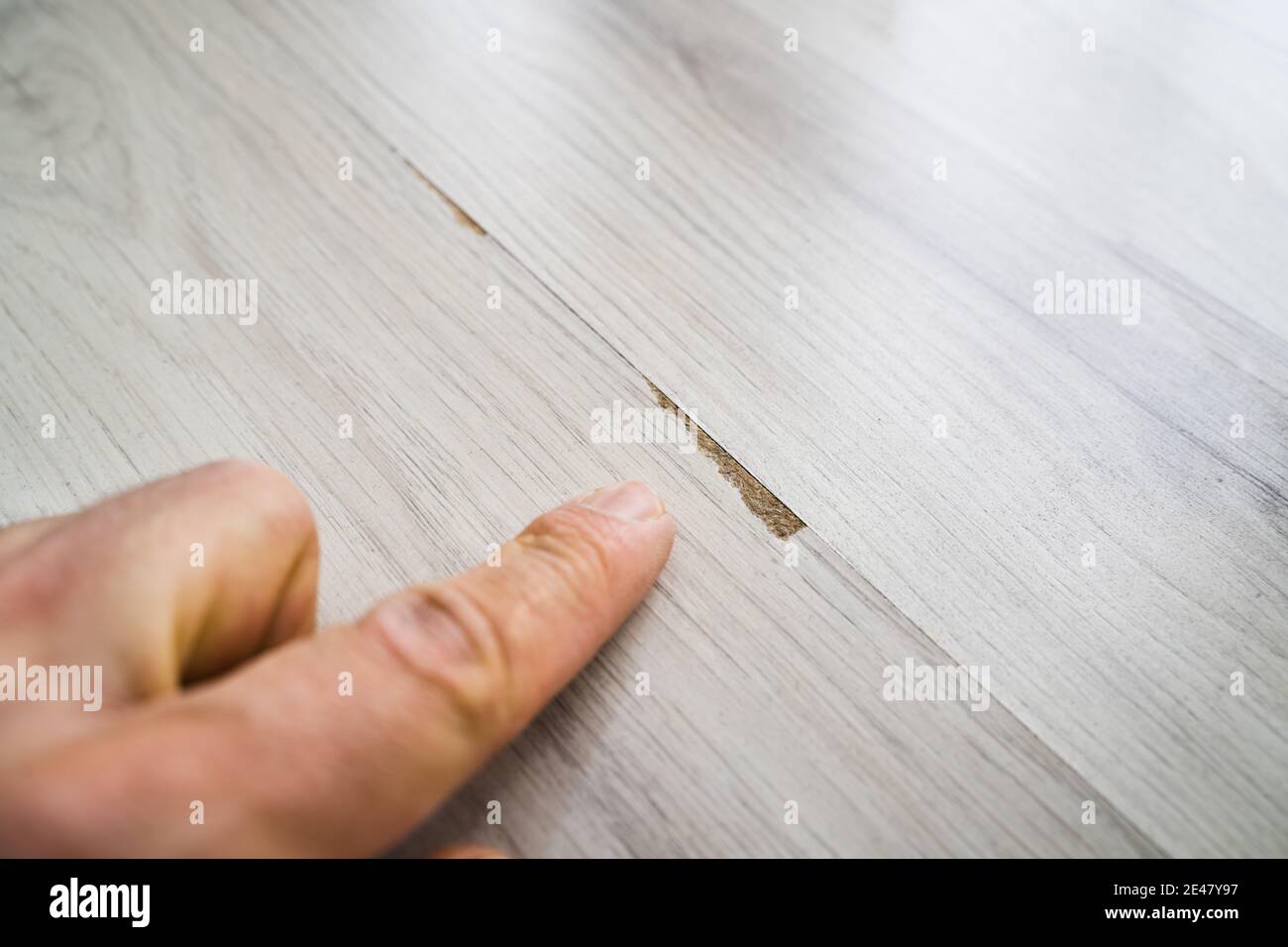 Hand Zeigt Auf Beschädigte Alte Laminat Bodenbelag Oberfläche Zu Hause Stockfoto