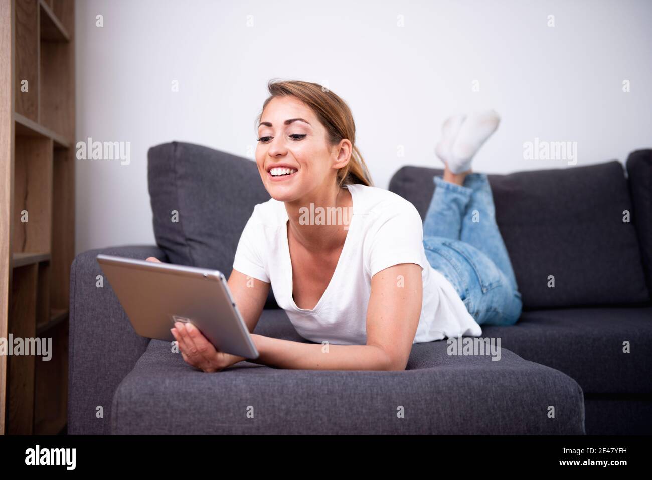 Schöne Frau mit ihrem Tablet auf einem Sofa in einem Wohnzimmer Stockfoto