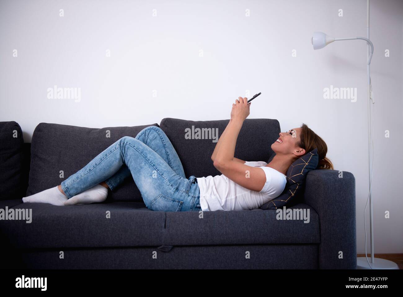 Schöne Frau mit ihrem Smartphone in ihrem Wohnzimmer Stockfoto