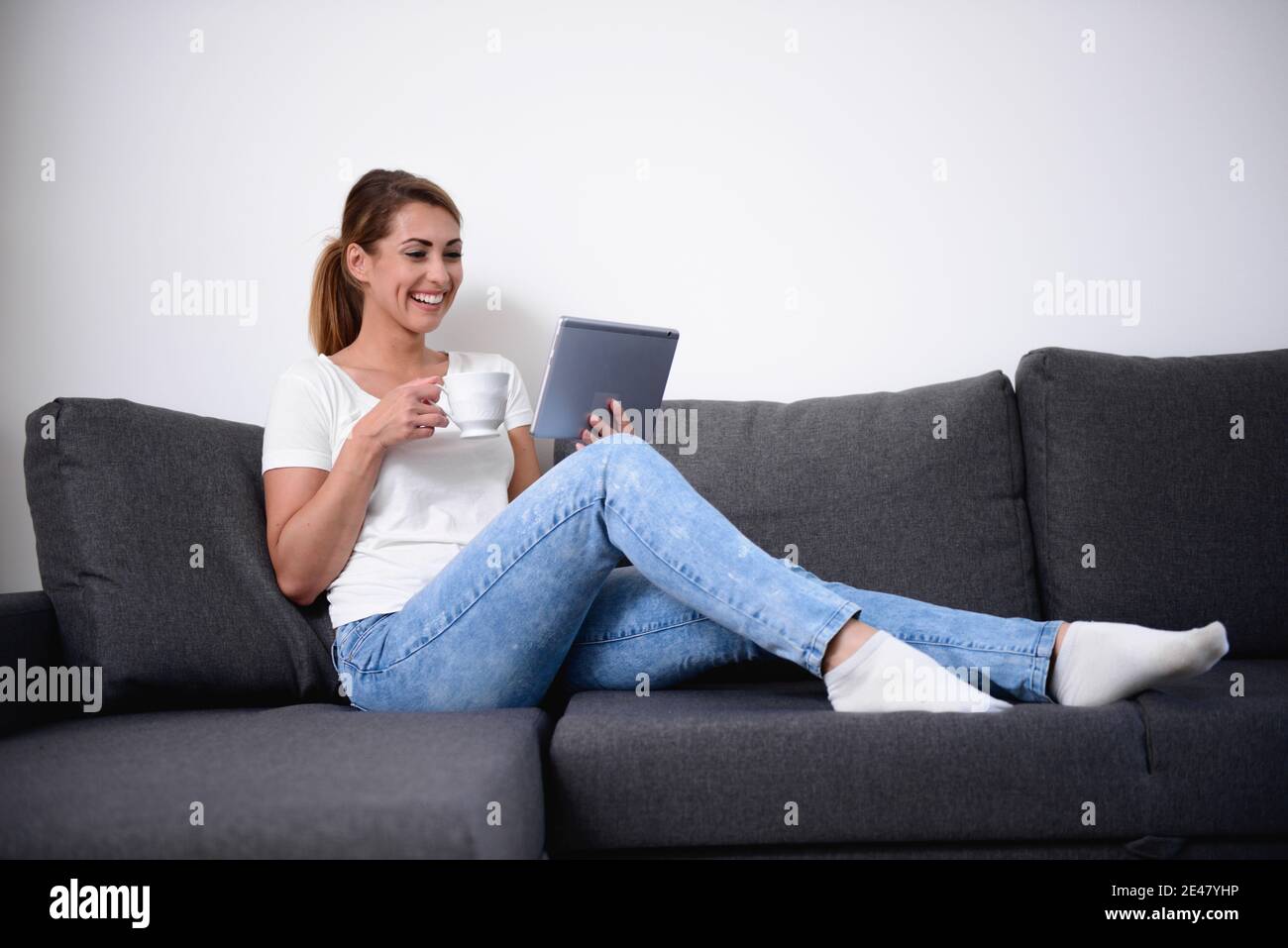 Schöne Frau mit ihrem Tablet auf einem Sofa in einem Wohnzimmer Stockfoto