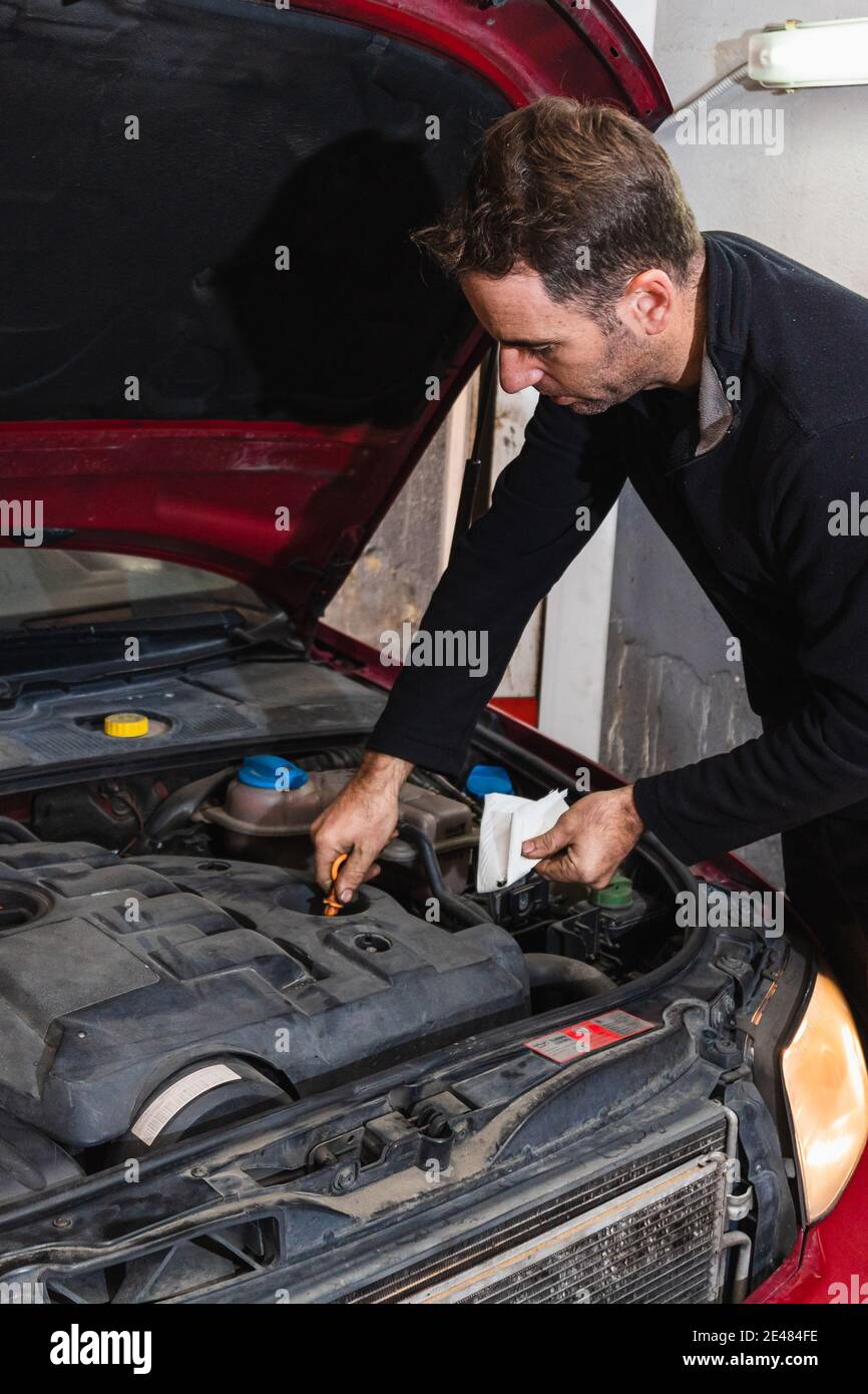 Mechaniker, der den Ölstand im Motor des Autos betrachtet. Konzept der Automechanik Stockfoto