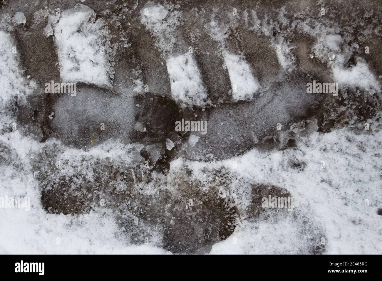 Eisige Fußabdruck und Autospuren auf Schnee und Eis Überdachte Straße Stockfoto