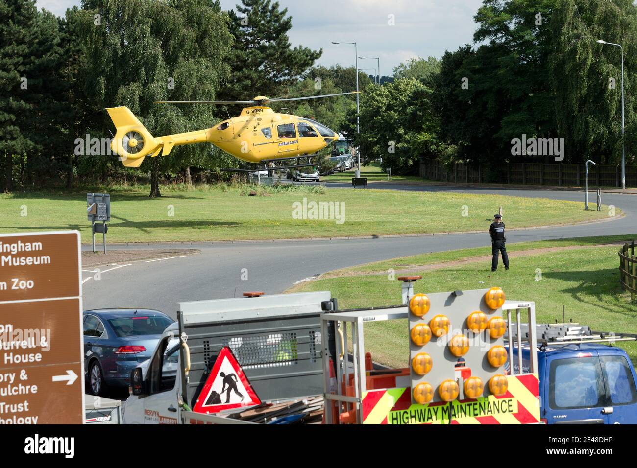 Der Rettungshubschrauber East Anglian Air Ambulance landet auf einem britischen Autobahnumkreisel, um eine verletzte Person ins Krankenhaus zu bringen. Stockfoto