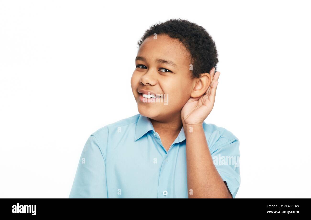 Afroamerikanischer Junge hält die Hand am Ohr zum Hören, isoliert auf weißem Hintergrund. Hörtestkonzept Stockfoto