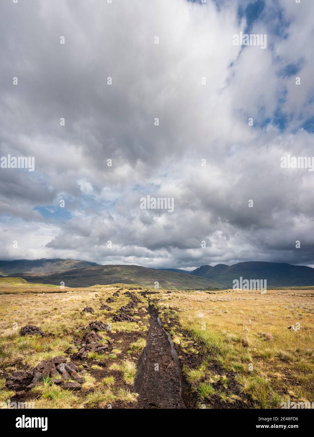 Torfstapel (Rasen) zum Heizen, Trocknen auf gesägter Moor in Bunowen, in der Nähe von Killar Harbor, Connemara, Grafschaft Galway, mit Mweelrea Mountains in der Ferne Stockfoto