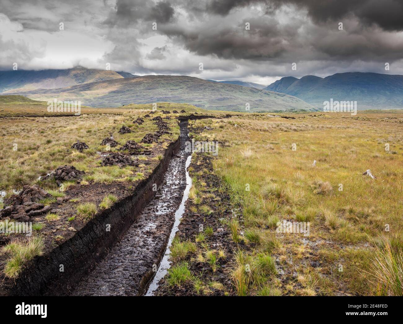 Torfstapel (Rasen) zum Heizen, Trocknen auf gesägter Moor in Bunowen, in der Nähe von Killar Harbor, Connemara, Grafschaft Galway, mit Mweelrea Mountains in der Ferne Stockfoto