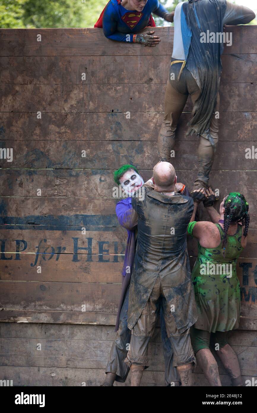 Schlammige Beine rutschen und rutschen überall wie Sie versuchen, eine rutschige Holzbarriere während einer zu klettern Ausdauer-Event „Tough Mudder“ Stockfoto