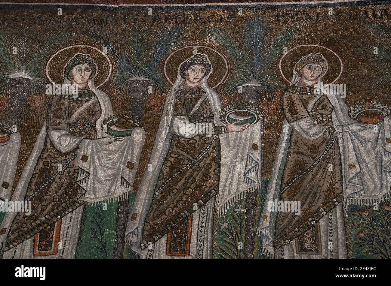 Drei von 22 mit Juwelen geschmückten und prächtig gekleideten weiblichen christlichen Heiligen, die in einer Prozession laufen. Detail des byzantinischen Mosaiks in der Basilica di Sant’Apollinare Nuovo in Ravenna, Emilia-Romagna, Italien. Das Mosaik entstand in den 500er Jahren n. Chr., wenige Jahre nachdem Ravenna von den Ostgoten erobert wurde. Stockfoto