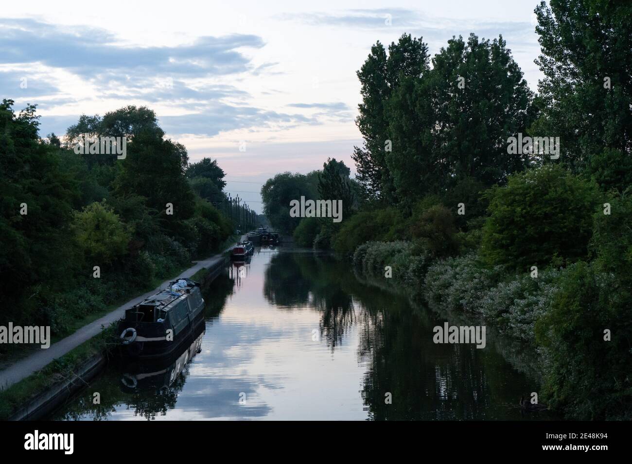 Zwei Kanalboote auf dem Fluss in der Abenddämmerung umgeben von Bäumen Schöner Sonnenuntergang spiegelt sich im Sommer in immer noch frischem Wasser wider Stockfoto