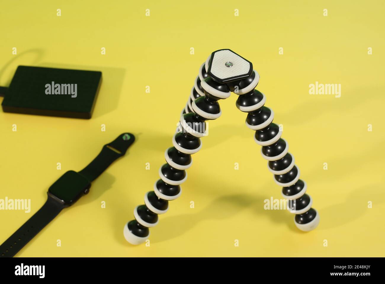 Gorilla Stativ mit Smartwatch und externer Festplatte auf einem Gelber Hintergrund Stockfoto