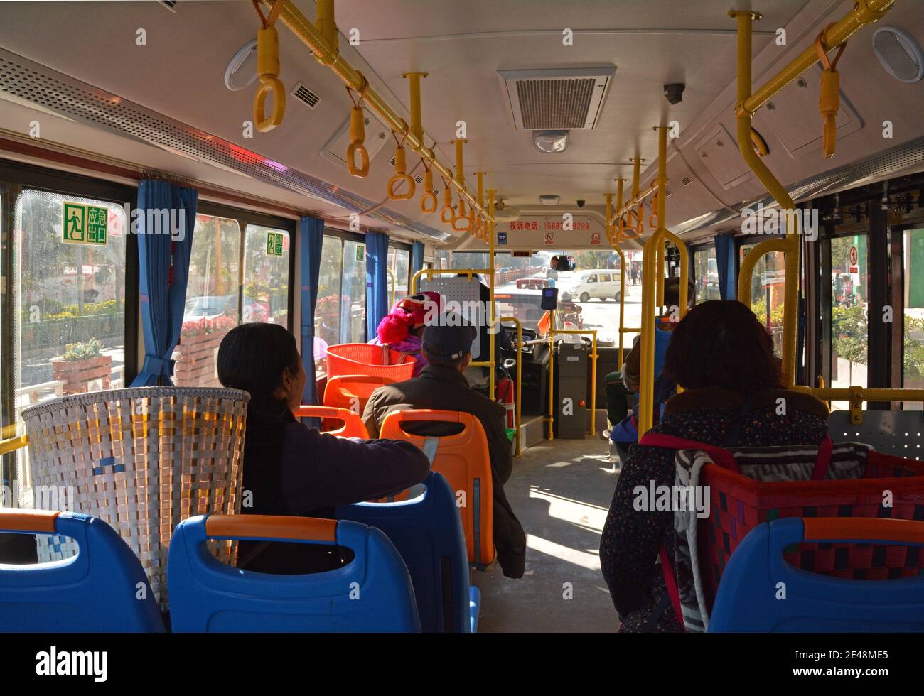Damen im Bus in Shangri La, China, fahren mit ihren traditionellen Körben auf dem Rücken auf den Markt. Gemeinsame Frau in dieser Stadt mit Körben zu sehen. Stockfoto